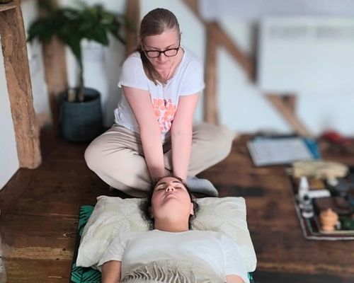 Johanna placing hands on a person’s head during a healing session, representing relaxation and energetic support