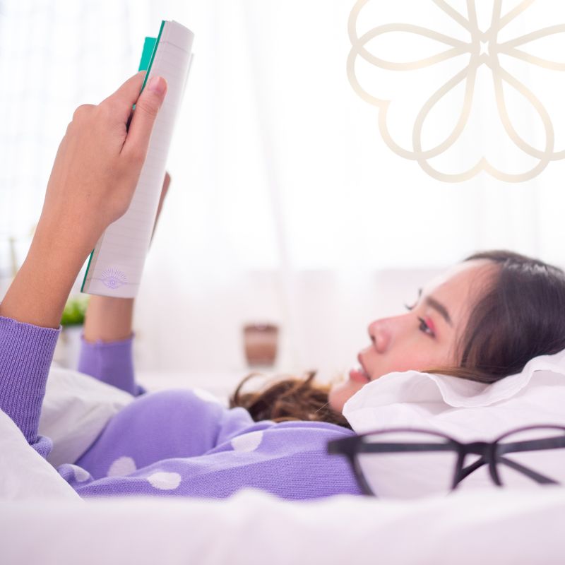Person lying in bed reading a notebook, representing reviewing session recap notes and personal insights