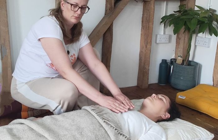 Johanna placing hands on a person’s chest during a healing session, representing relaxation and energetic support