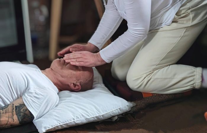 Shamanic energy healer placing hands over a person’s face during a healing session, representing restoring balance and energetic flow