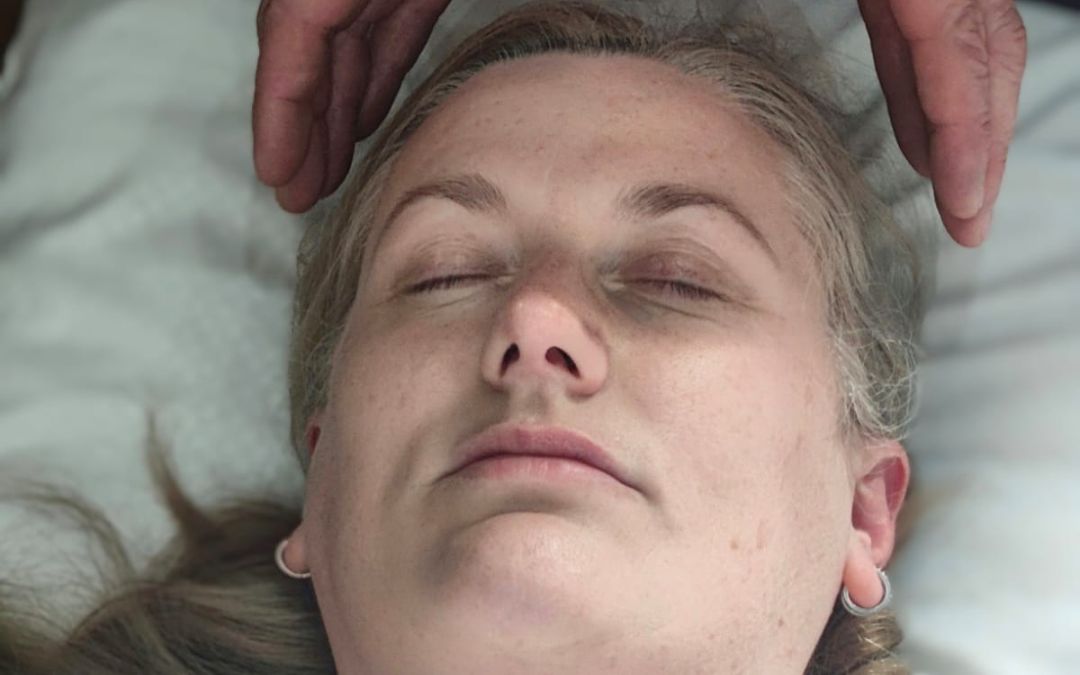 Soie-2019-healing Shamanic energy healer holding hands above Johanna's head during a healing session, representing calm, grounding and energetic support