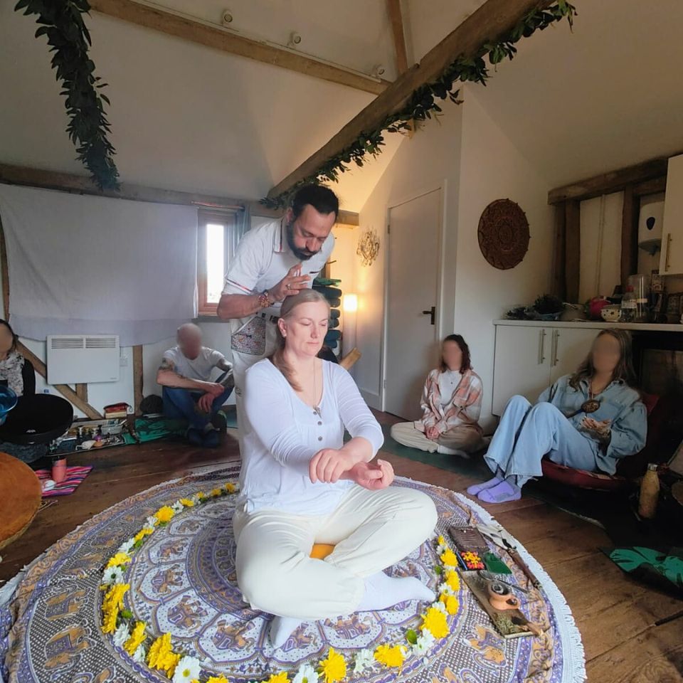 Johanna sitting cross-legged during a group energy healing session with others seated around her in a circle